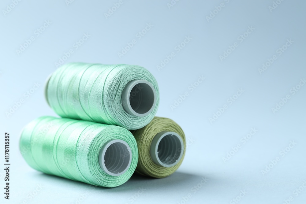 Spools of colorful sewing threads on light background, closeup. Space for text Spools of colorful sewing threads on light background, closeup. Space for text