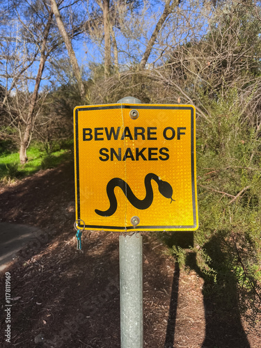 Yellow sign warns of snake danger in wooded trail area in Melbourne photo