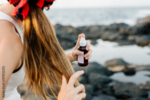 Woman spraying a texturizing hair spray over her hairstyle photo