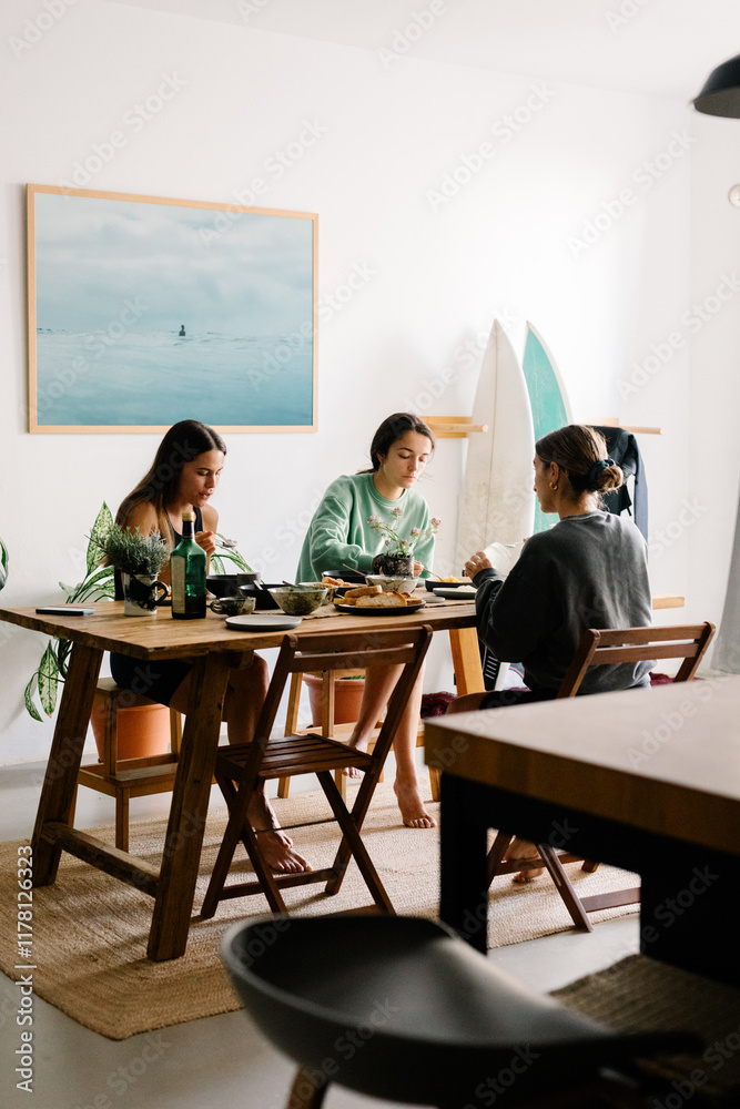 Friends gathered around a dining table enjoying breakfast together Friends gathered around a dining table enjoying breakfast together