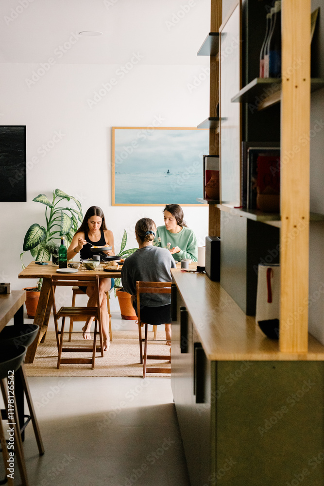 Three friends having breakfast together, sitting at a dining room Three friends having breakfast together, sitting at a dining room