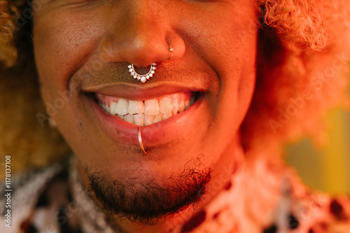 Close-up of smiling lips with facial piercings in warm lighting photo