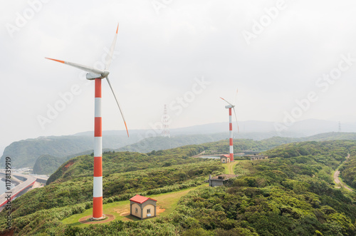 Wind turbines on a lush green hill with small buildings photo