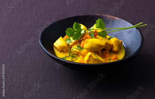 Delicious yellow curry with chicken and vegetables served in a bowl photo