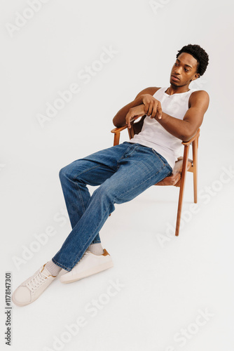 Man in casual cothes sitting in a wooden chair in studio photo