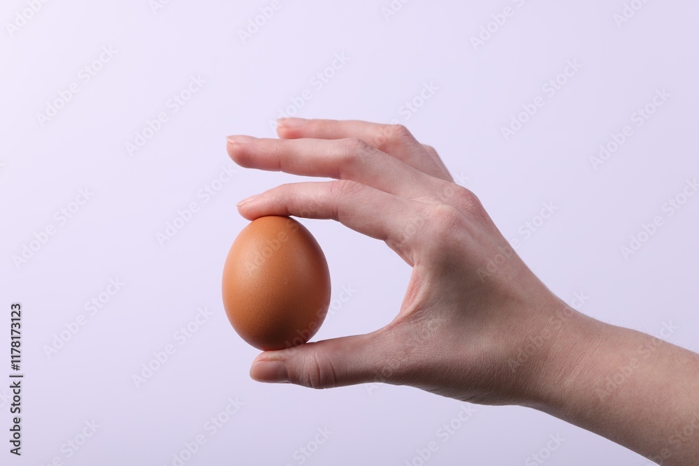 Woman holding raw egg on light background, closeup Woman holding raw egg on light background, closeup