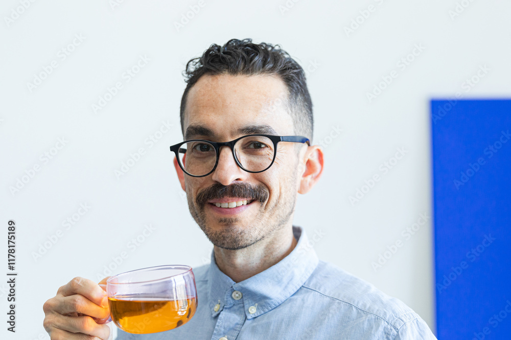 Man with glasses enjoying a cup of tea, smiling brightly Man with glasses enjoying a cup of tea, smiling brightly