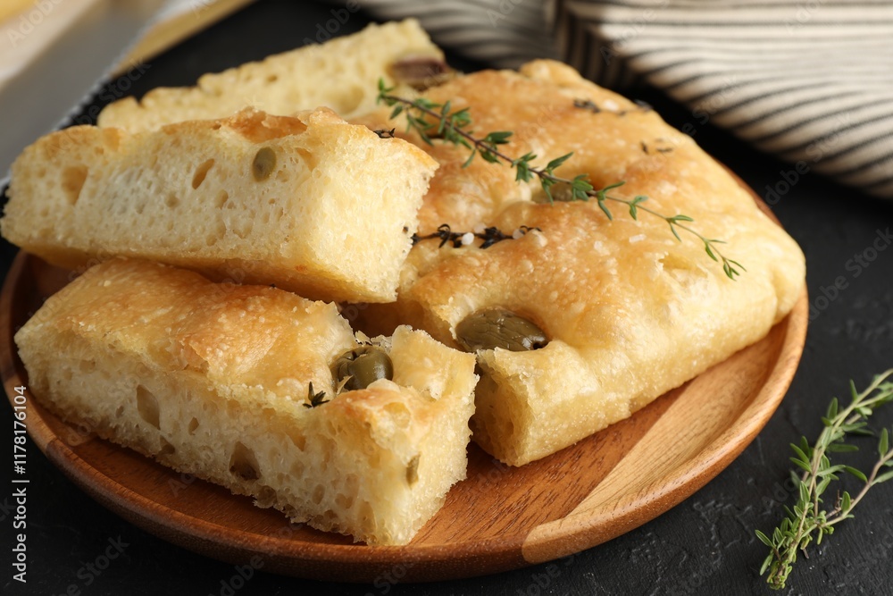 Slices of delicious focaccia bread with olives, thyme and salt on black table, closeup Slices of delicious focaccia bread with olives, thyme and salt on black table, closeup