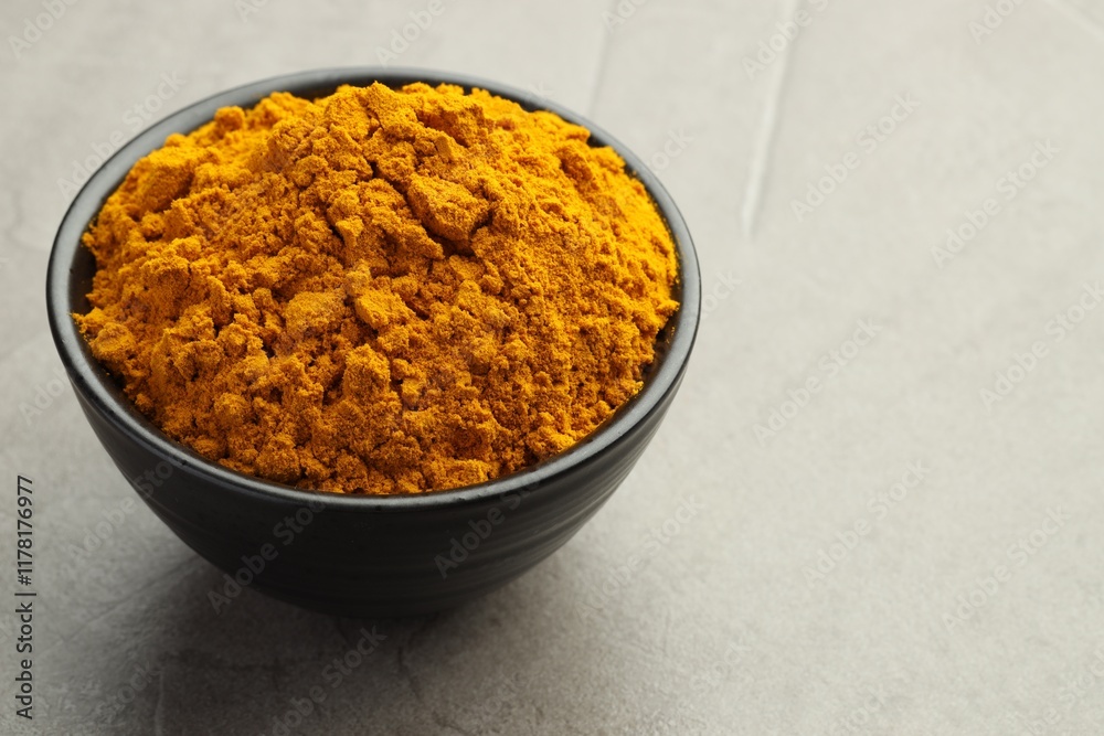 Turmeric powder in bowl on grey table, closeup. Space for text Turmeric powder in bowl on grey table, closeup. Space for text