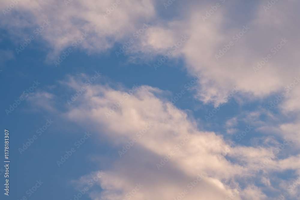Fototapeta premium Soft fluffy clouds drift across a pale blue sky