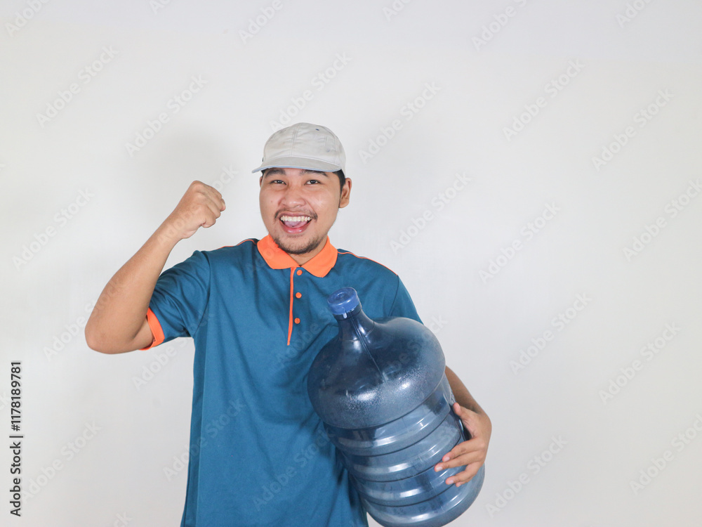 A happy Asian delivery courier is carrying a gallon or big water bottle of mineral water with a red gesture of success while raising his hand A happy Asian delivery courier is carrying a gallon or big water bottle of mineral water with a red gesture of success while raising his hand