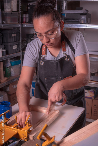 Young white-skinned Latina woman doing printing work using the screen printing and printing with meshes method. It could be for industry or sales. Advertising uses different tools or objects. She is h