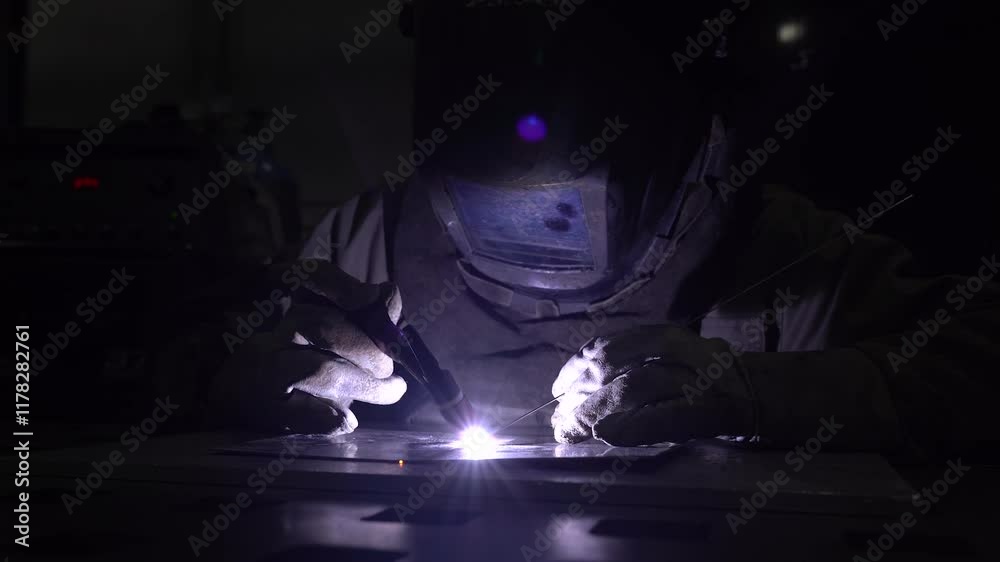 Welder welds stainless steel and metal using the TIG method in white gloves Welder welds stainless steel and metal using the TIG method in white gloves