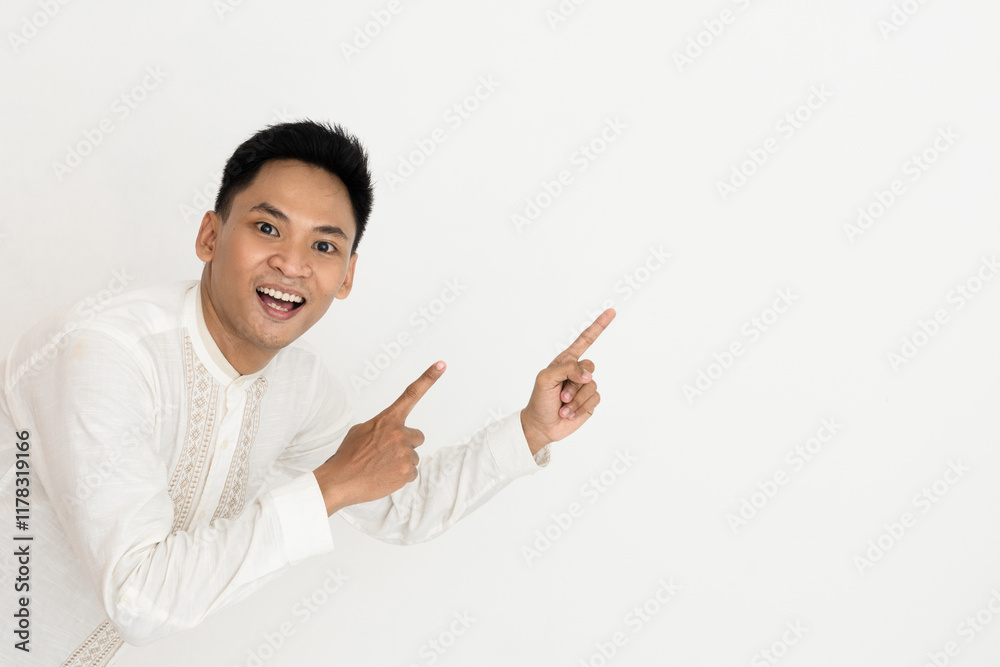 Cheerful man pointing up with excitement and energy, wearing a traditional white outfit, over white background, suggesting possibilities such as notices, advertising, or announcements Cheerful man pointing up with excitement and energy, wearing a traditional white outfit, over white background, suggesting possibilities such as notices, advertising, or announcements