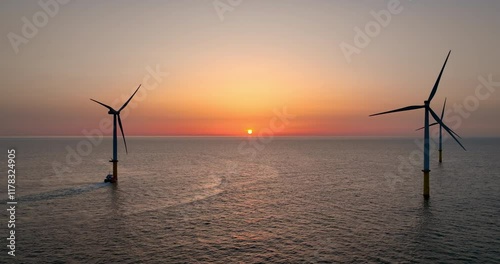空撮 - 夕焼けの海と海上風力発電所　複数の風車　右ドリー