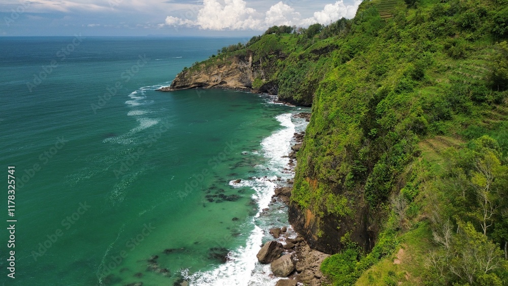 Aerial drone view of coastline with hills and trees, as well as view of coral cliffs and sea with waves from the ocean in Menganti Beach Kebumen Central Java Indonesia Aerial drone view of coastline with hills and trees, as well as view of coral cliffs and sea with waves from the ocean in Menganti Beach Kebumen Central Java Indonesia