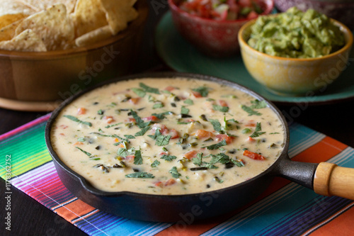 Tex-Mex Restaurant Chile Con Queso Dip in cast iron skillet with guacamole, salsa and tortilla chips