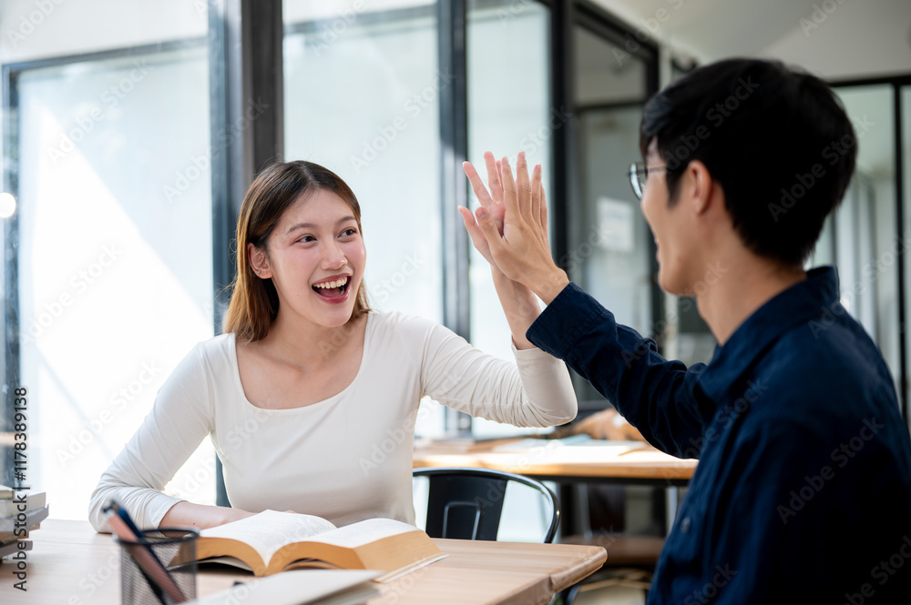 Two cheerful Asian students are giving each other a high five to celebrate their exam success. Two cheerful Asian students are giving each other a high five to celebrate their exam success.
