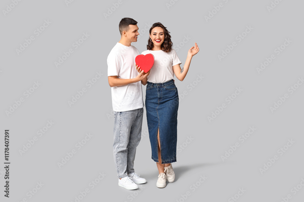 Loving young couple with gift box on grey background. Celebration of Saint Valentine's Day Loving young couple with gift box on grey background. Celebration of Saint Valentine's Day