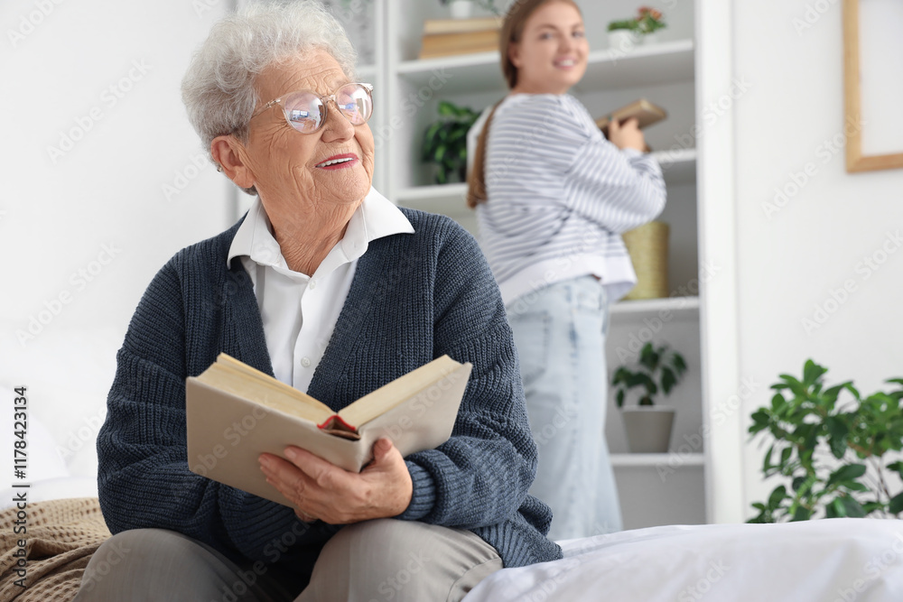 Happy senior woman and her granddaughter reading books in bedroom at home Happy senior woman and her granddaughter reading books in bedroom at home