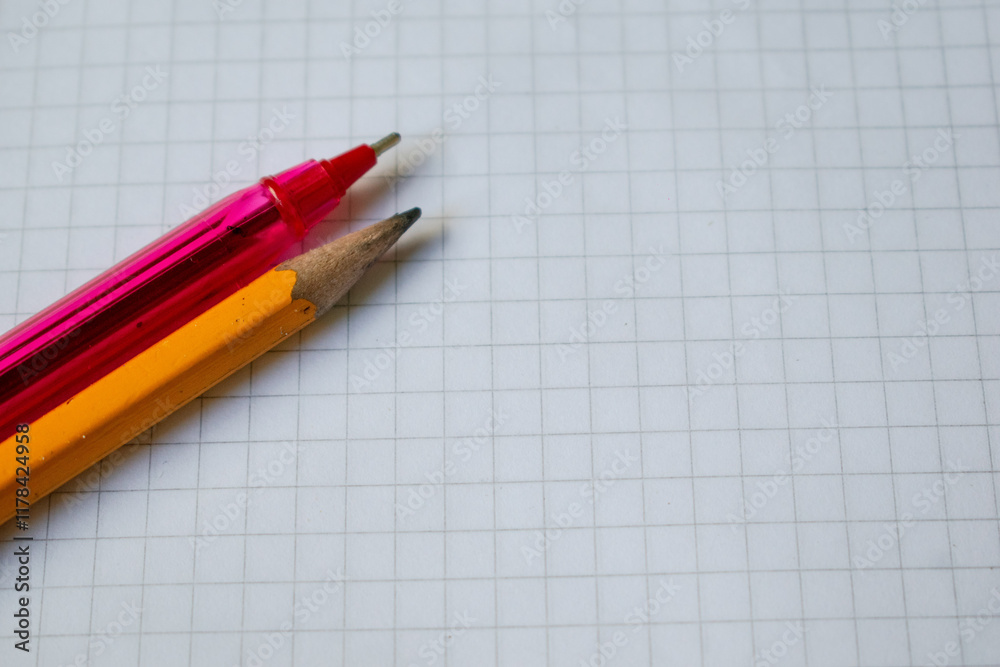 A pencil and red pen placed on a white grid paper sheet, symbolizing creativity, writing, and organization. This simple and versatile image is perfect for projects related to education, stationery A pencil and red pen placed on a white grid paper sheet, symbolizing creativity, writing, and organization. This simple and versatile image is perfect for projects related to education, stationery