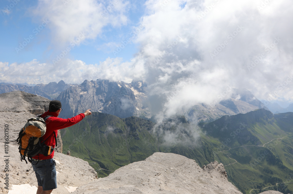backpacking hiker pointing toward the summit of Mount Marmolada in summer in northern Italy on the European Alps backpacking hiker pointing toward the summit of Mount Marmolada in summer in northern Italy on the European Alps