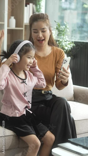 Asian young mother and her daughter sit together on the sofa in the cozy living room, working on homework at the desk, creating a warm and supportive atmosphere for learning, love, hug, mother days.