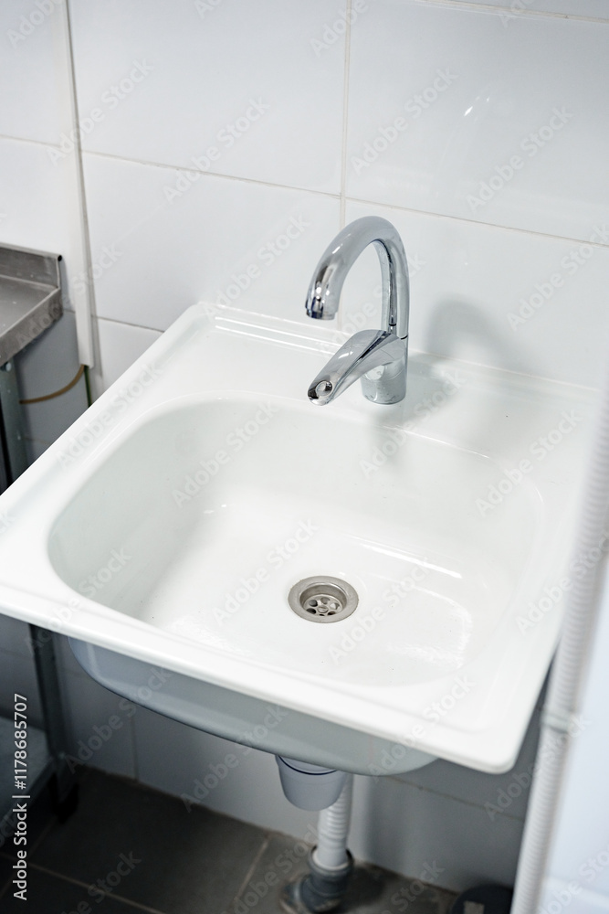 Modern white sink with a sleek faucet design in a clean bathroom environment Modern white sink with a sleek faucet design in a clean bathroom environment