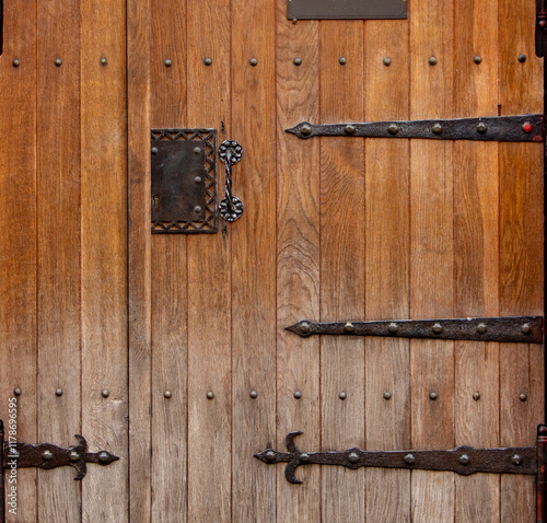 Close up of old wooden doors with heavy metal hinges in stone building