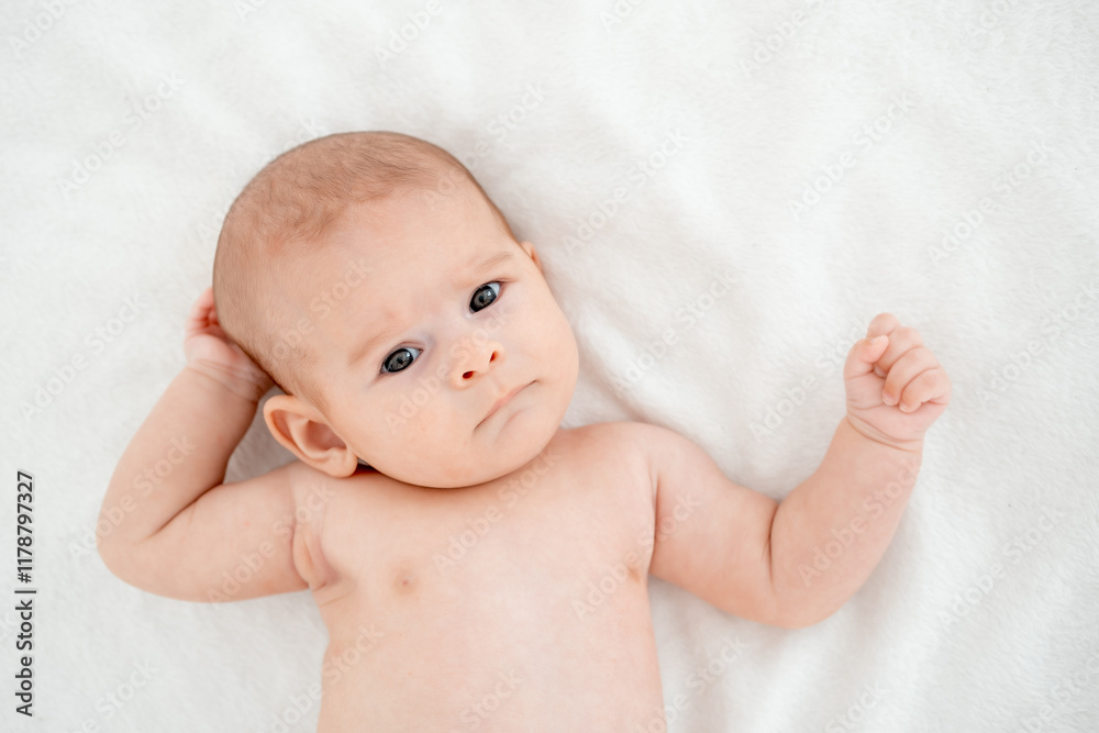 Newborn baby girl naked on a white bed at home lying on her back, close-up portrait, place for text Newborn baby girl naked on a white bed at home lying on her back, close-up portrait, place for text