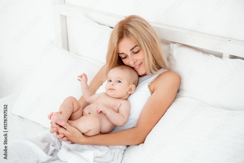 mom and baby hug and kiss, a young mother gently hugs a newborn baby girl holding her in her arms on the bed, maternal love and care, mother and daughter, a place for text. mom and baby hug and kiss, a young mother gently hugs a newborn baby girl holding her in her arms on the bed, maternal love and care, mother and daughter, a place for text.