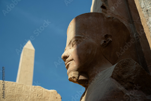Statue of a pharaoh with an abelisk in the background in Luxor
