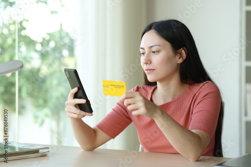 Serous asian woman buying online in a room photo