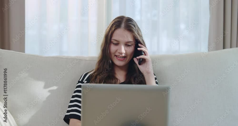 Woman Working on Laptop and Talking on Phone  at Home