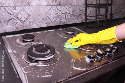 Woman cleaning gas stove with sponge and detergent. Cleaning kitchen. Housework and cleaning service concept.