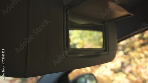 Close-up of interior rear view mirror against yellow leaves background