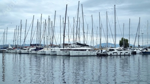 Fotografie A marina filled with white sailboats and yachts, reflecting on calm water beneat