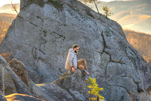 Climber with a beard sitting on a rock looking at the landscape in the highlands surrounded by mountain walls photo