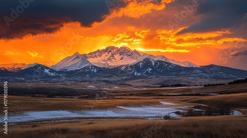A dramatic sunset casting a golden glow over a snowy mountain range, creating a breathtaking contrast.