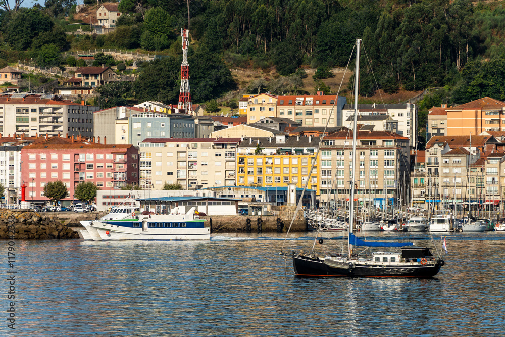Boats by the coast on Marina of Moana with residential houses in the background, Galicia, Spain