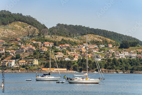 Obraz na płótnie Boats by the coast on Marina of Moana with residential houses in the background, Galicia, Spain w salonie