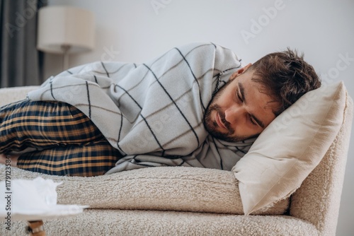 Cold, lying down under the blanket. Sick man is feeling bad at home