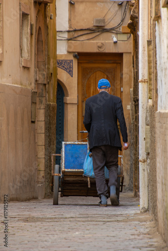 Man pushing his small cart in a small street in Essaouira in Morocco
