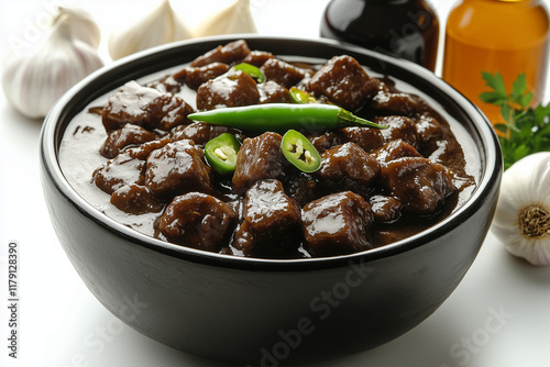 Dinuguan with green chili in a black bowl on a light background photo