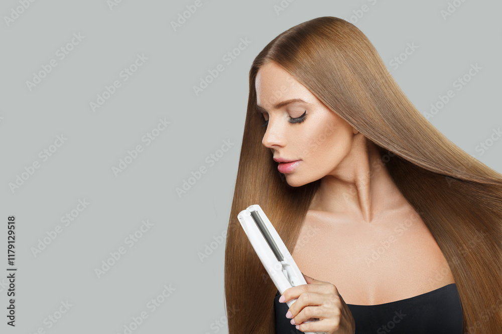 Glamorous brunette woman holding straight hair iron and straightening her long smooth shiny hair on white background. Haircare, hairstyle, hairdressing and hair styling concept Glamorous brunette woman holding straight hair iron and straightening her long smooth shiny hair on white background. Haircare, hairstyle, hairdressing and hair styling concept