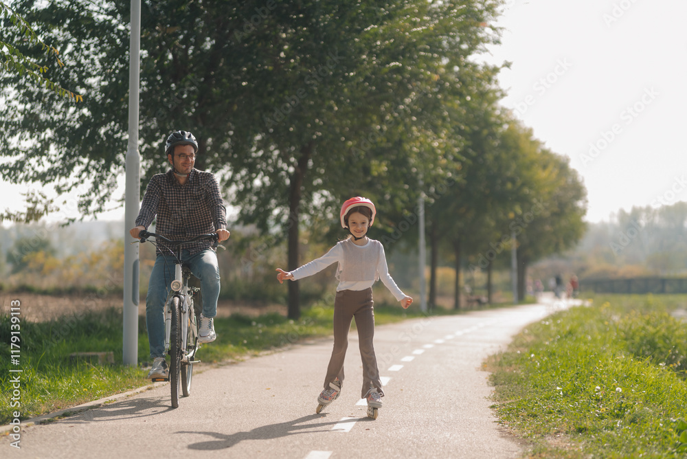 Fototapeta premium Father and daughter enjoying roller skating and cycling in a park
