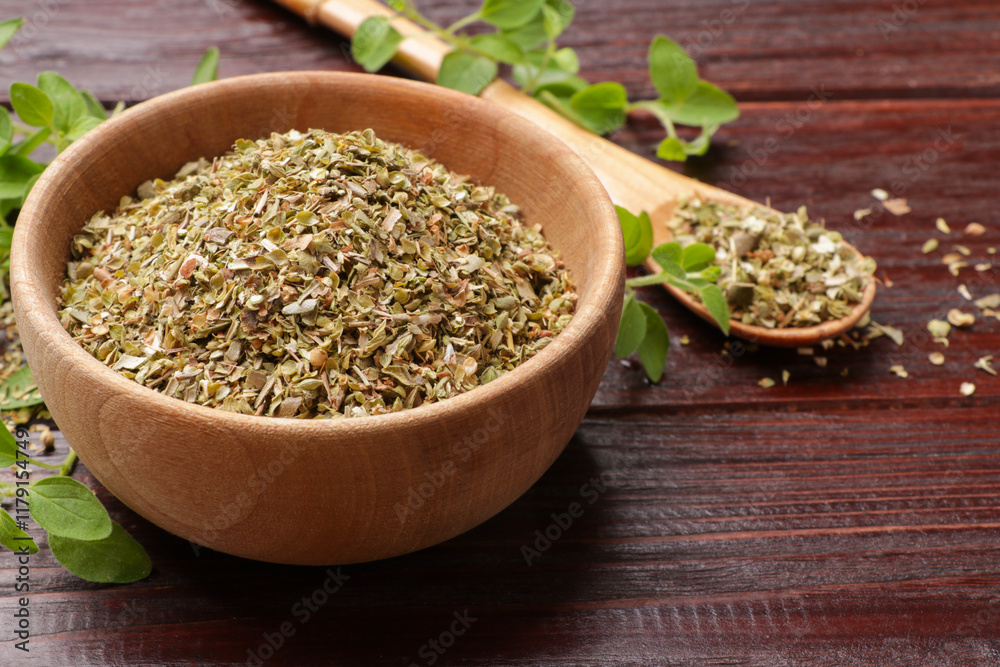Dried oregano in bowl, spoon and green leaves on wooden table, closeup Dried oregano in bowl, spoon and green leaves on wooden table, closeup