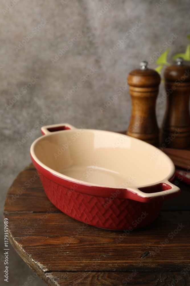 Ceramic casserole and shakers on wooden table, closeup Ceramic casserole and shakers on wooden table, closeup