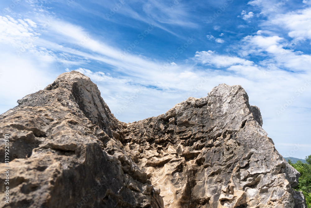 Dramatic rocky outcrop with layered texture under a blue sky with wispy white clouds Dramatic rocky outcrop with layered texture under a blue sky with wispy white clouds