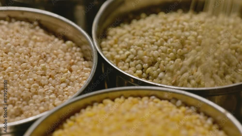 filling brown top millet in steel bowl with foxtail millet and little millet for storage, 4k, stable shot
